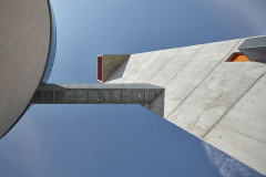 Štíhlá zvonice z pohledového betonu má trojúhelníkový půdorys
